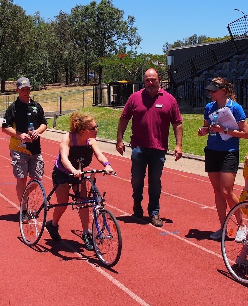  Dr Sarah Reedman (QCPRRC Researcher), Richard Keith (Chairperson for RaceRunning Australia), Malcolm Davidson (Dejay Medical), working with athlete Tarsha on RaceRunning. 